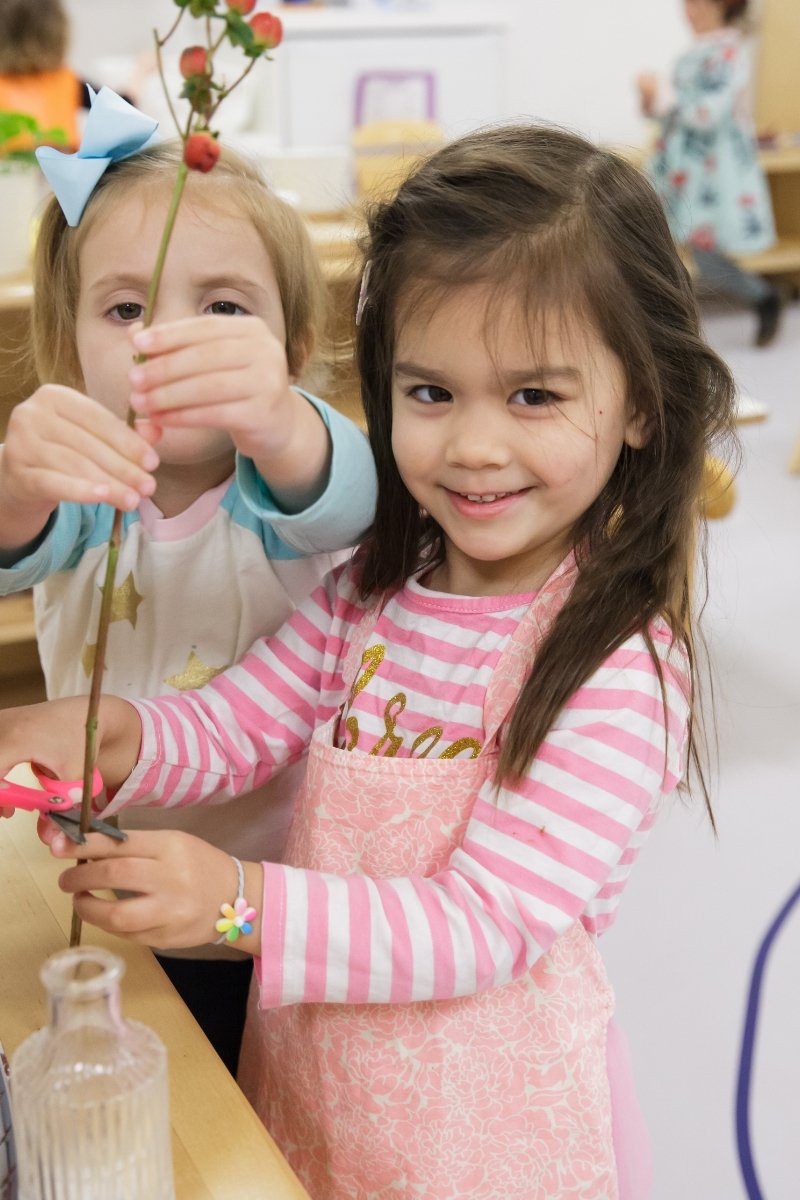 2 students putting flowers in a vase